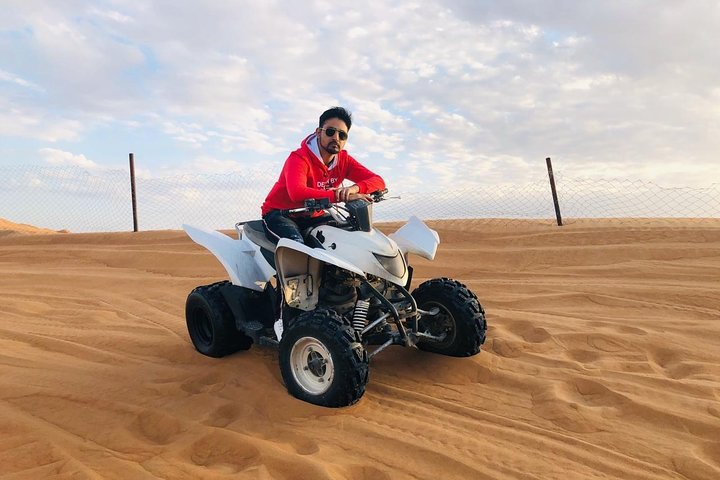 Experience the thrill of conquering the sandy dunes on an ATV surrounded by the stunning desert landscape of Dubai where adventure meets breathtaking scenery in the morning light.